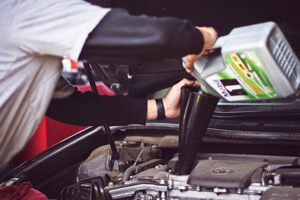 Mechanic topping up fluids under the hood