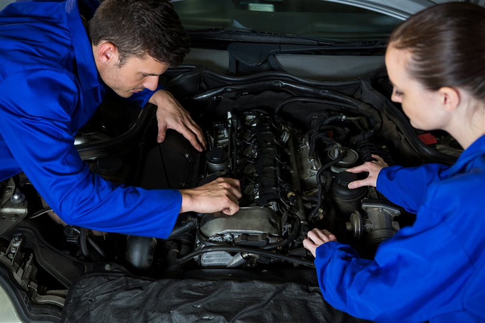 Two mechanics working on a car engine