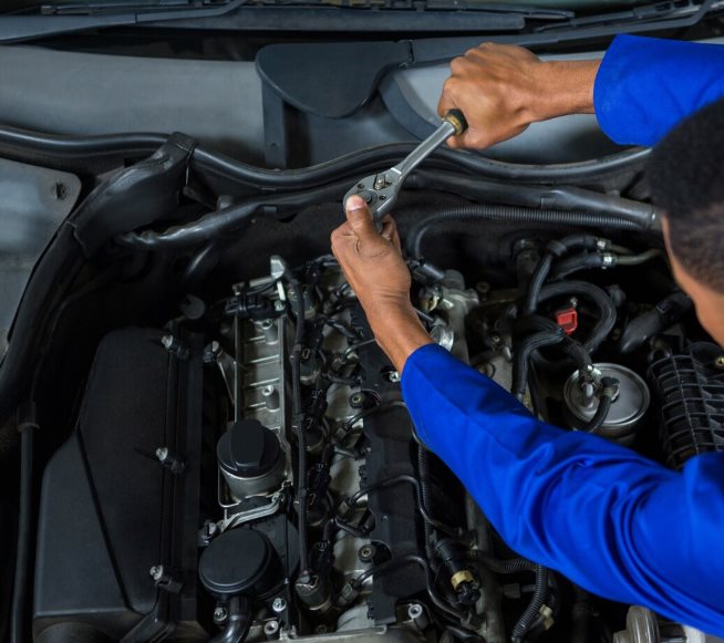 Mechanic tightening bolts in an engine bay